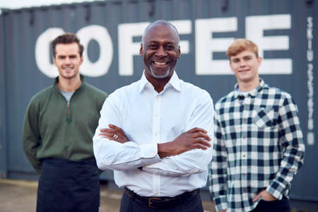Portrait Of Male Multi-Cultural Freight Haulage Team Standing By Shipping Containerの写真素材