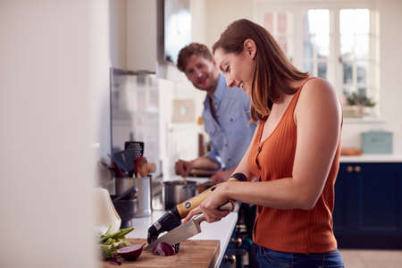 Couple With Woman With Prosthetic Arm In Kitchen Preparing Meal Togetherの写真素材