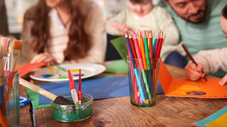 Close Up Of Family With Down Syndrome Daughter Sitting Around Table At Home Doing Craft Togetherの写真素材