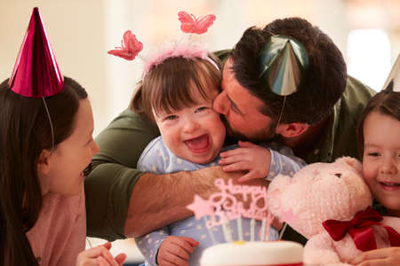 Family With Down Syndrome Daughter Celebrating Birthday With Party At Home Together