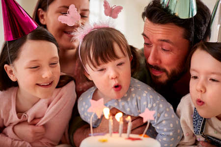 Family With Down Syndrome Daughter Celebrating Birthday With Party At Home Togetherの写真素材