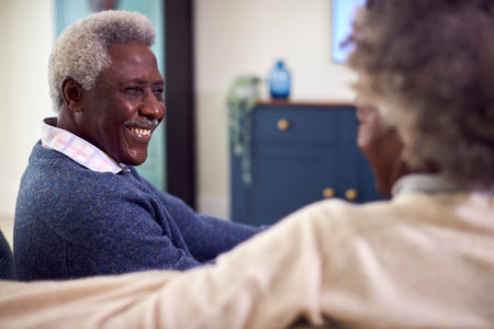 Senior Couple Sitting On Sofa Watching Movie On TV At Homeの写真素材