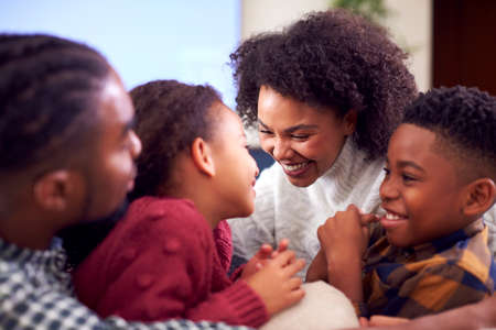 Family Sitting On Sofa Having Fun Watching Movie On TV At Home