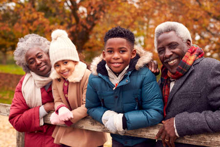 Portrait Of Grandparents By Gate With Grandchildren On Walk Through Autumn Countryside Togetherの写真素材