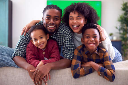 Portrait Of Family Sitting On Sofa Watching Movie On Green Screen TV At Homeの写真素材