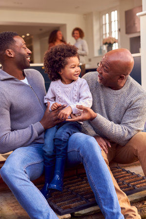 Grandfather With Father And Son Sit On Step At Home Putting On Boots Before Going On Family Walkの写真素材