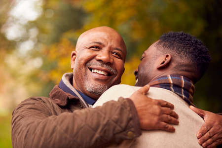 Loving Senior Father Hugging Adult Son On Walk Through Autumn Countrysideの写真素材