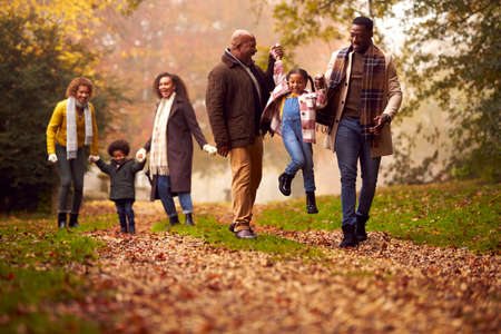 Smiling Multi-Generation Family Having Fun With Children Walking Through Autumn Countryside Togetherの写真素材