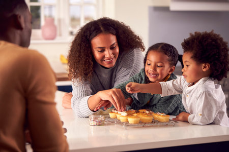 Family Baking Cupcakes Sitting Around Kitchen Counter At Homeの写真素材