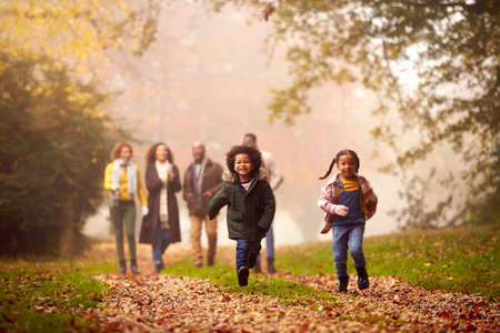 Smiling Multi-Generation Family Having Fun With Children Walking Through Autumn Countryside Togetherの写真素材