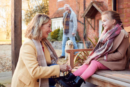 Grandparents With Granddaughter Outside House Getting Ready To Go For Winter Walkの写真素材