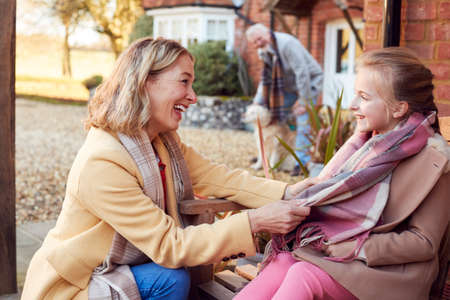 Grandparents With Granddaughter Outside House Getting Ready To Go For Winter Walkの写真素材