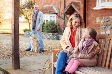 Grandparents With Granddaughter Outside House Getting Ready To Go For Winter Walkの写真素材