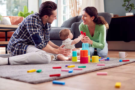 Transgender Family With Baby Playing Game With Colourful Toys In Lounge At Homeの写真素材