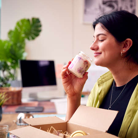 Woman Running Online Business From Home Smelling Packing And Packing Boutique Candles For Shipping
