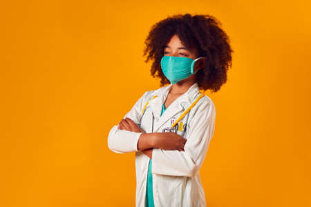Studio Portrait Of Boy Dressed As Doctor Or Surgeon Against Yellow Backgroundの写真素材