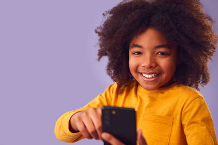 Studio Portrait Of Young Boy Using Mobile Phone Against Purple Backgroundの写真素材