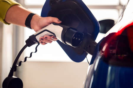 Close Up Of Hand Attaching Charging Cable To Environmentally Friendly Zero Emission Electric Carの写真素材