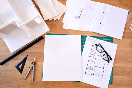 Overhead Shot Of Desk In Architects Office With Plans Drawing Instruments And Model
