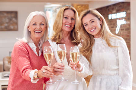 Portrait Of Grandmother With Adult Daughter And Granddaughter Trying On Wedding Dress In Storeの写真素材