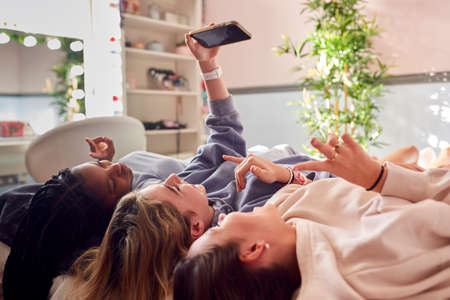 Group Of Smiling Multi-Cultural Teenage Girl Friends Posing For Selfie On Mobile Phone At Home