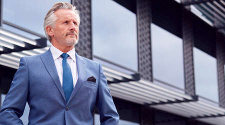 Portrait Of Serious Senior Businessman CEO Chairman Standing Outside Modern Office Building