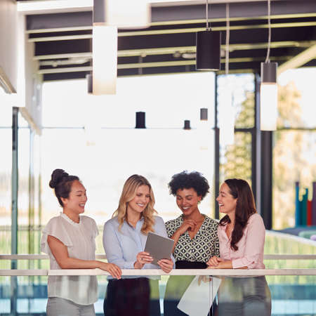 Multi-Cultural Female Business Team With Digital Tablet Meeting Inside Modern Office Buildingの写真素材