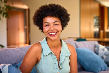 Portrait Of Confident Smiling Woman Relaxing On Sofa At Homeの写真素材