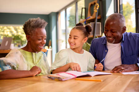 Multi-Generation Family With Grandparents Helping Granddaughter With School Work At Home
