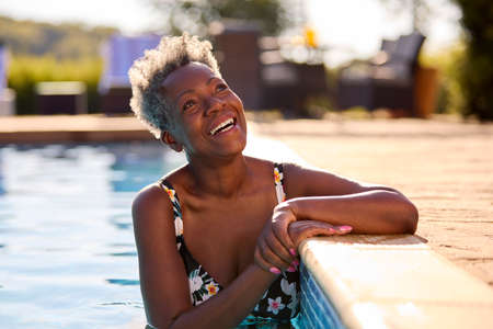 Smiling Senior Woman On Summer Holiday Relaxing In Swimming Poolの写真素材