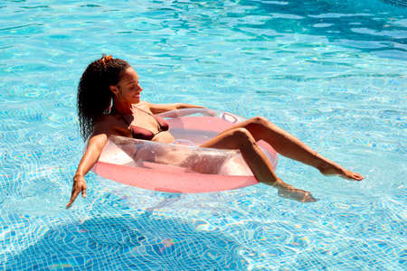 Woman On Summer Holiday Floating On Inflatable In Swimming Pool