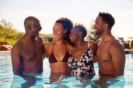 Multi-Generation Family With Adult Offspring On Summer Holiday Relaxing In Swimming Pool Together