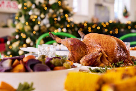 Table At Home Set For Christmas Lunch With Roast Turkey And Vegetables With Decorationsの写真素材