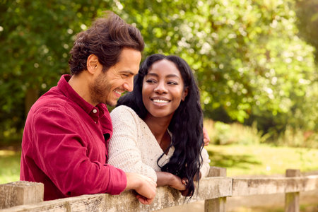 Loving Mixed Race Couple Leaning On Fence On Walk In Countrysideの写真素材