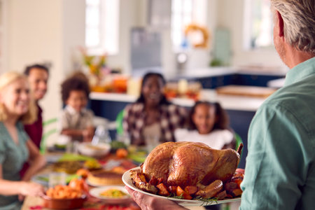 Grandfather Serving As Multi-Generation Family Celebrating Thanksgiving At Home Eating Meal Togetherの写真素材