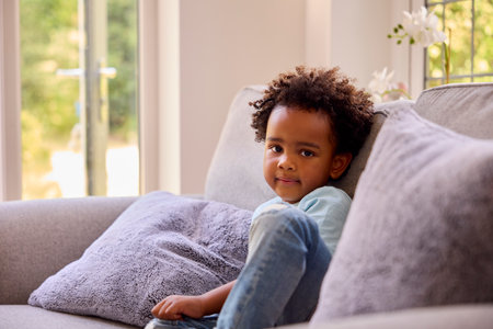 Portrait Of Young Boy Sitting On Sofa At Home