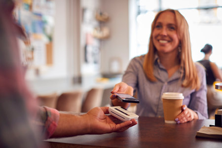 Female Customer Making Contactless Payment In Coffee Shop Using Mobile Phone