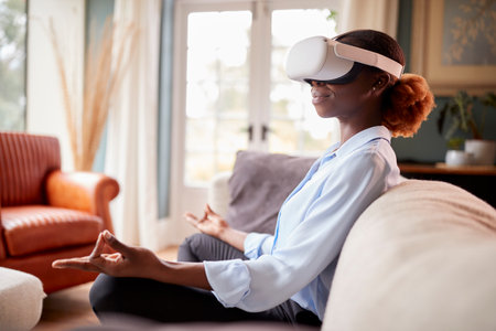 Woman Meditating On Sofa At Home Wearing VR Headset And Interacting With AR Technologyの写真素材