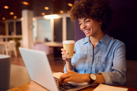 Young Businesswoman In Modern Open Plan Office Working On Laptop In Seating Pod With Coffeeの写真素材