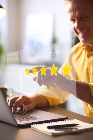 Man Using Laptop With Graphic Overlay To Leave Positive 5 Star Online Reviewの写真素材