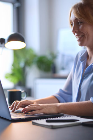 Close Up Of Woman Typing On Laptop Keyboard Sitting At Deskの写真素材