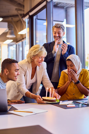 Staff Celebrating Birthday Of Female Colleague Wearing Headscarf In Office With Cake