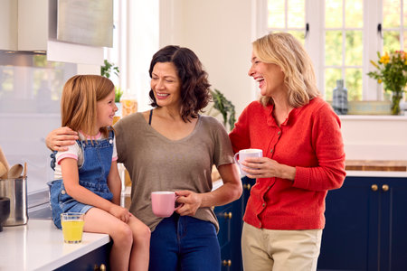 Same Sex Family With Two Mature Mums And Daughter Sitting In Kitchen Talking Together