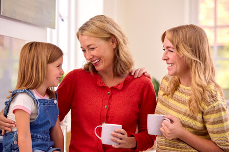 Same Sex Family With Two Mature Mums And Daughter Sitting In Kitchen Talking Together