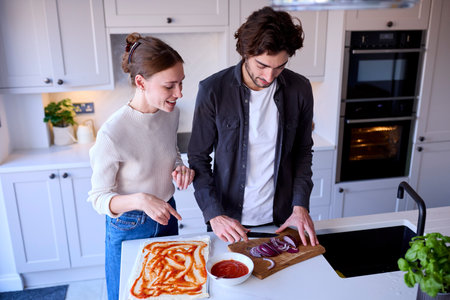 Couple In Kitchen At Home Making Homemade Pizza Togetherの写真素材