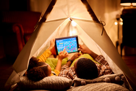 Father And Daughter At Home Lying In Indoor Tent Or Camp Gaming On Digital Tablet