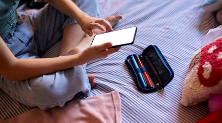Close Up Of Diabetic Girl Sitting On Bed At Home Checking Insulin Levels On Mobile Phone App