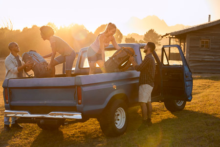 Group Of Friends Unloading Backpack From Pick Up Truck On Road Trip To Cabin In Countrysideの写真素材