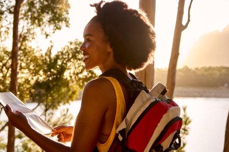 Woman With Map And Backpack On Vacation Hiking By Lake At Sunsetの写真素材