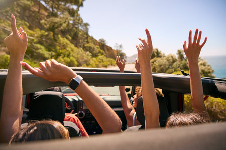 Group Of Laughing Female Friends Putting Hands Through Sunroof Open Top Car On Road Tripの写真素材